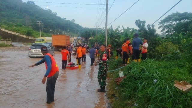 Sertu Aan Asrori Dengan Sigap Mengatur Lalu lintas Di Titik Terparah Genangan